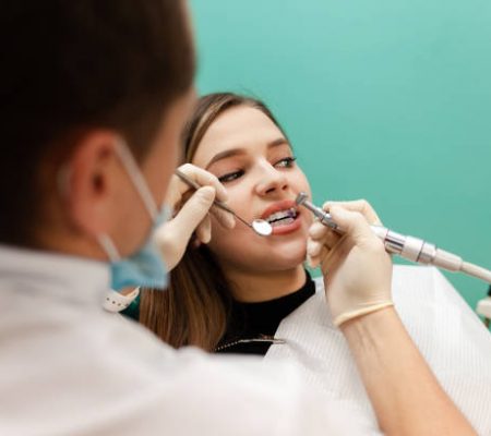 Dentist performs professional polishing of tooth enamel for woman patient